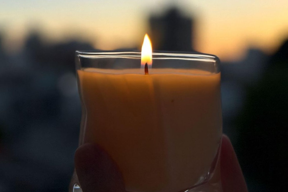 hand holding a lit candle against a twilight sky, a simple total solar eclipse self-care ritual