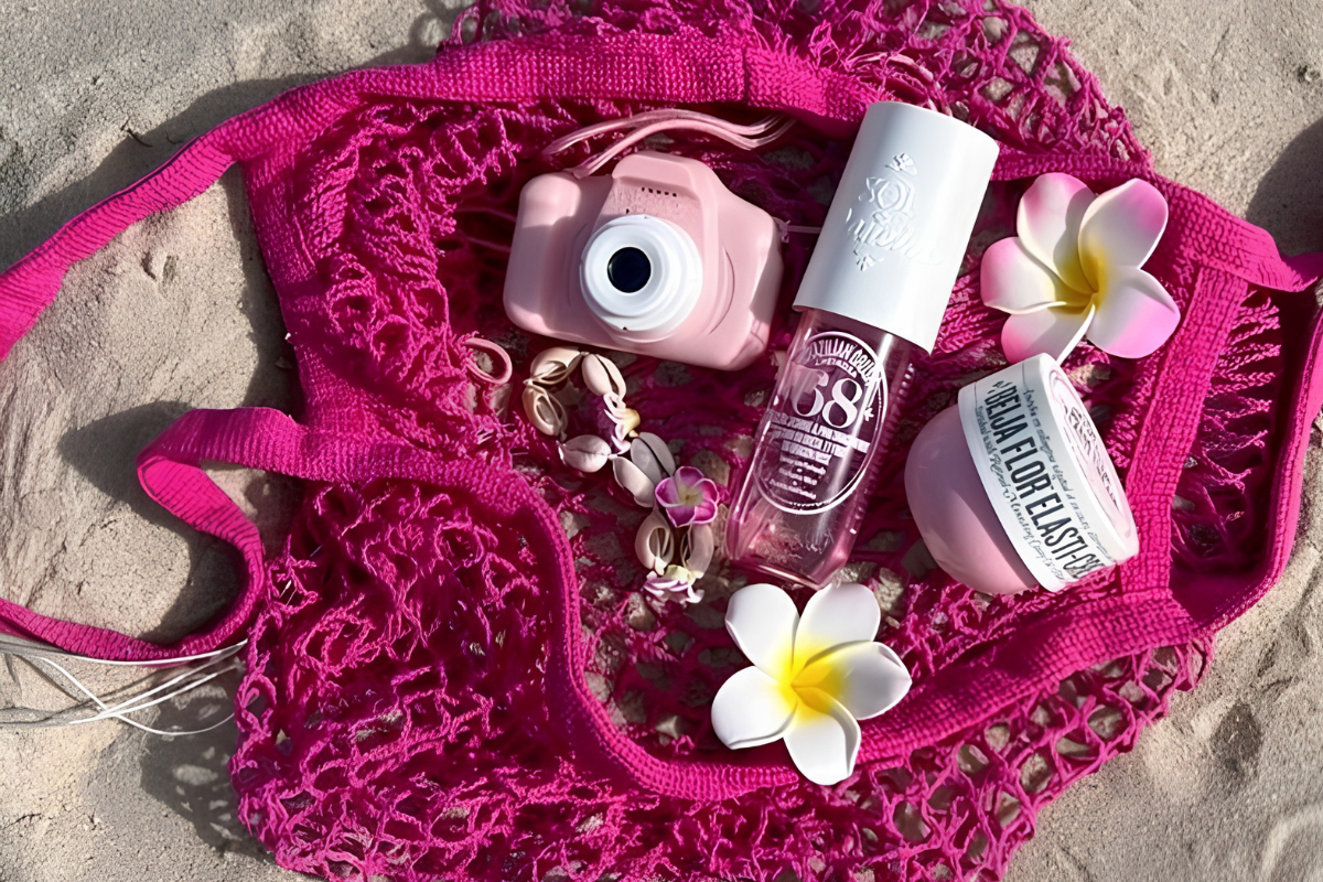 flatlay of a pink beach bag with a camera, fragrance, and flowers - small ways to feel more like yourself this summer