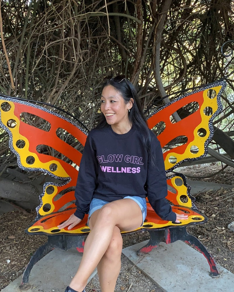 Stepha on the butterfly bench in a Glow Girl Wellness sweatshirt - About page hero
